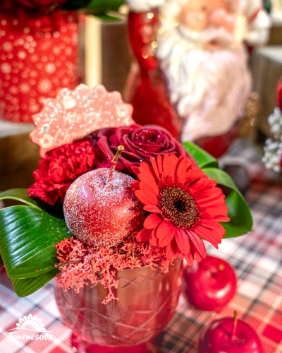 Composition florale rouge avec fleurs et décorations de Noël.